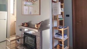 A kitchen with a built-in oven, a wooden shelf with books, and a framed painting on the wall. - Casa Chiara (Picenze di Barisciano)