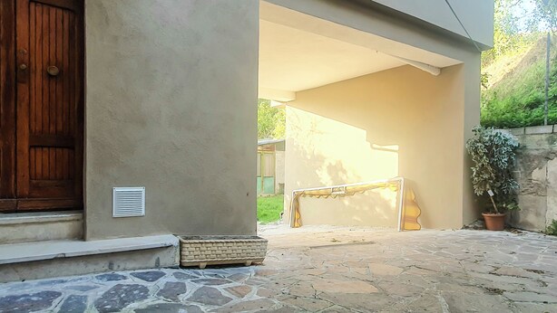 A stone-paved entrance with a wooden door, a vent, and a potted plant. - Casa Chiara (Picenze di Barisciano)