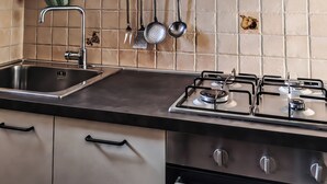 A kitchen with a stainless steel sink, a gas stove, and hanging utensils. - Casa Chiara (Picenze di Barisciano)