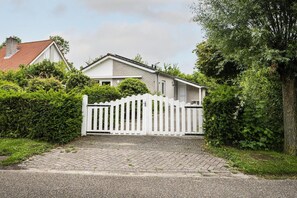 A residential house with a white picket fence, a paved driveway, and a red-tiled roof. - Coastal Bungalow Stay in Vlissingen (Vlissingen)