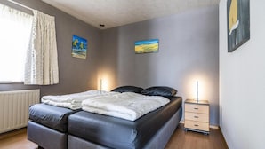 Ein Schlafzimmer mit einem Doppelbett, zwei Nachttischen, einem Heizkörper und zwei Bildern an der Wand.