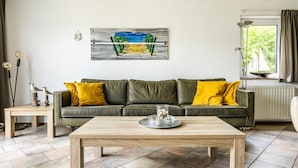 Ein Wohnzimmer mit einem grünen Sofa, einem Holztisch und einem Bild an der Wand.