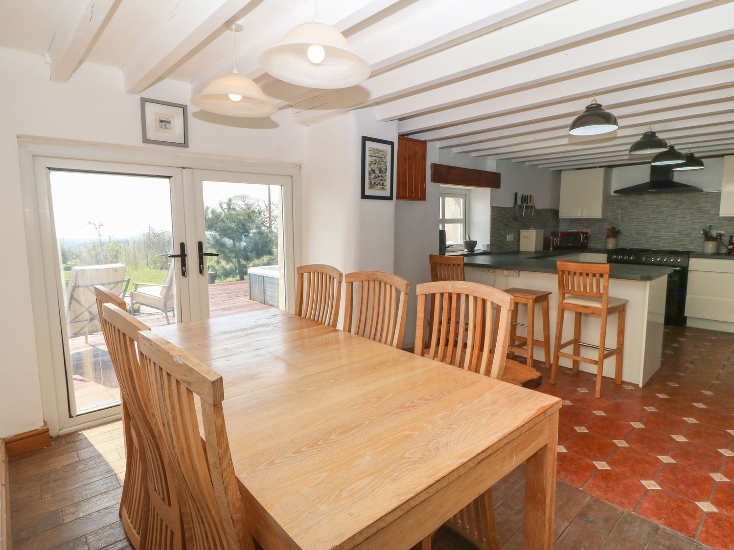 A dining area with a wooden table and chairs, a kitchen with a stove and sink, and a view through a glass door to an outdoor patio.