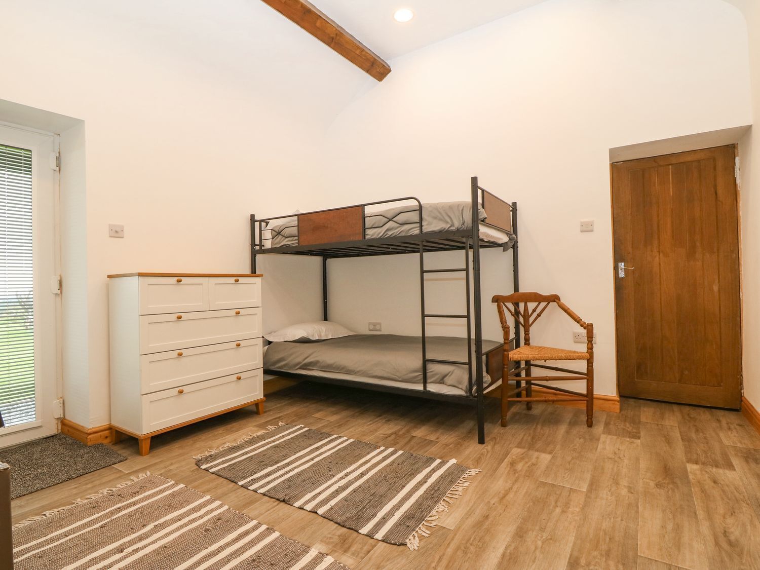 Habitación con literas, cómoda, silla y puerta.