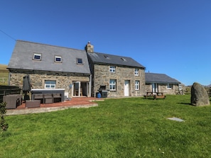 A stone house with a patio, outdoor seating, and a large rock in the yard. - Cefnbron (Caernarfon)