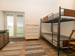 Habitación tipo dormitorio con literas, cómoda, silla y puerta que da al exterior.
