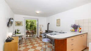 A compact kitchen with a dining area, a TV mounted on the wall, and a view of the outdoors. - Holiday home Batida Crikvenica by Villas Guide (Crikvenica)
