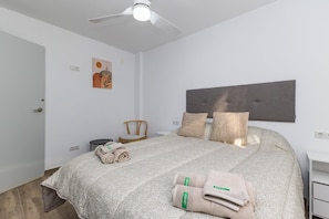 Un dormitorio con cama, una silla, un escritorio y un ventilador de techo.