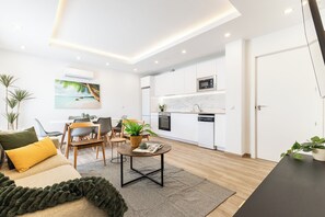 A modern living room with a dining area, kitchen, and a door leading to another room.