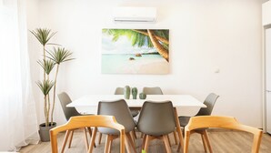 A dining area with a white table, grey chairs, and a painting of a beach scene. - Apartment at Origen Tepoztlán 8 (Torrent)