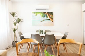 A dining area with a white table, grey chairs, and a painting of a beach scene. - Apartment at Origen Tepoztlán 8 (Torrent)