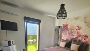 A modern bedroom with a bed, a desk, a television, and a large window.