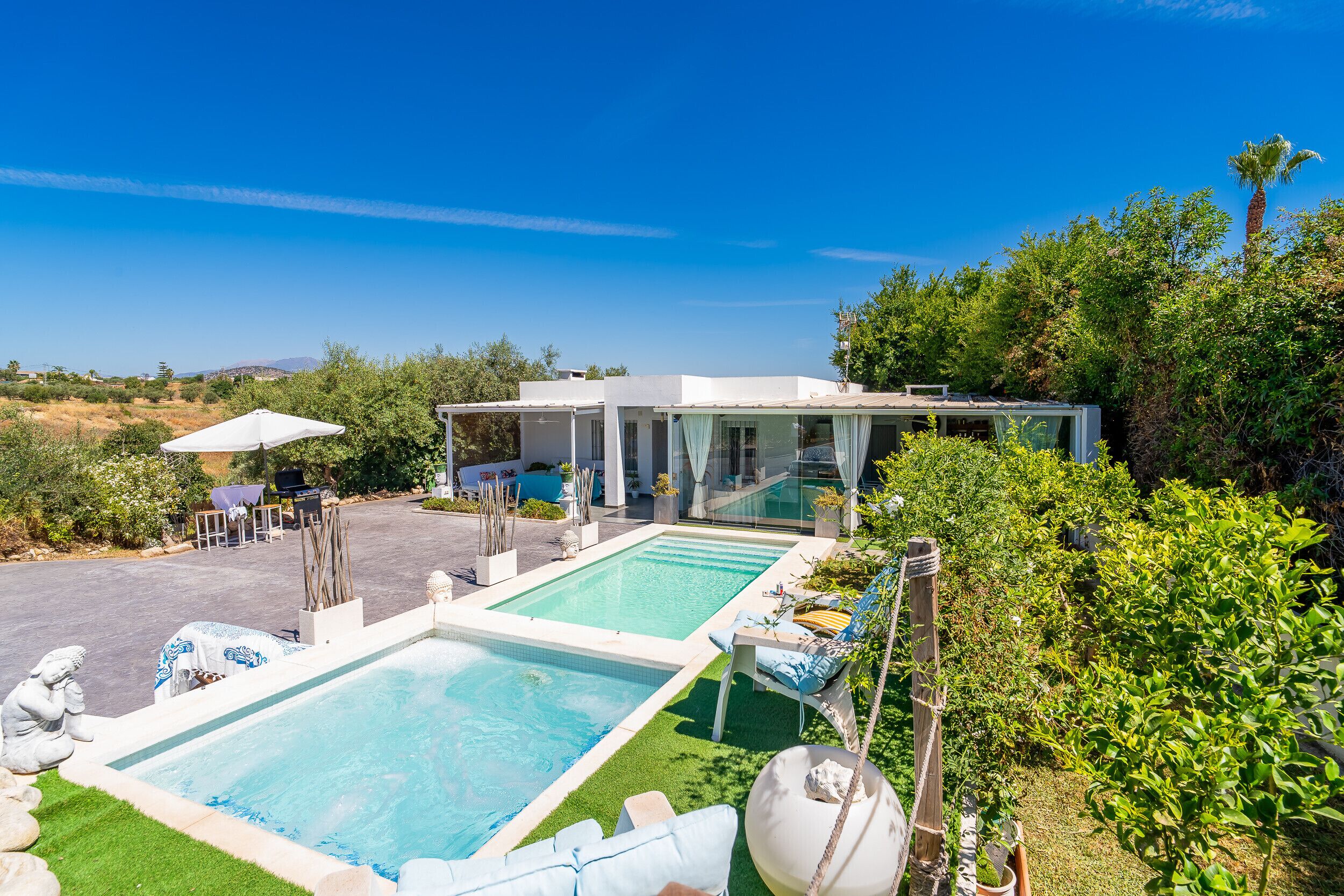 A pool area with two pools, lounge chairs, and a covered seating area.