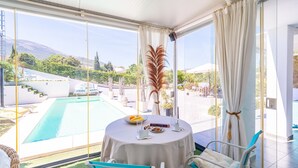 Ein Zimmer mit Blick auf den Pool, ein Tisch mit Frühstücksgebäck und ein Bett.