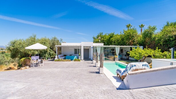 Ein modernes Haus mit Swimmingpool, Sitzgelegenheiten im Freien und einer überdachten Terrasse.