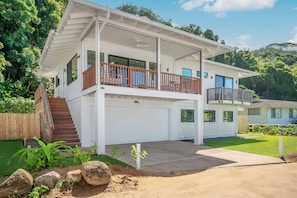 Ein zweigeschossiges Haus mit überdachter Veranda, Garage und einem angelegten Garten.