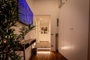 Ein Flur mit einer hölzernen Bank, einem Blumentopf, einem Wandbild und einer zur Toilette führenden Tür.