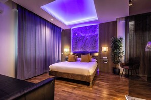 Ein modernes Schlafzimmer mit einem großen Bett, einer Deckenleuchte, einem an der Wand befestigten Fernseher und einem Blumentopf.