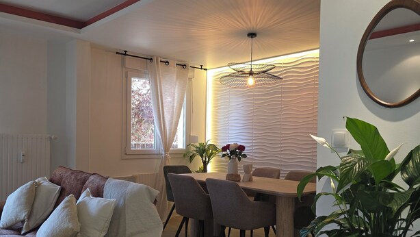 A modern living room with a sofa, dining table, chairs, a potted plant, and a ceiling light fixture. - Luxury Apartment • 3 Suites • 2 Parking Lots • 5 min Downtown (Strasbourg)