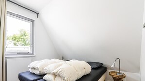 Un dormitori amb un llit, una finestra i una làmpada de nit.