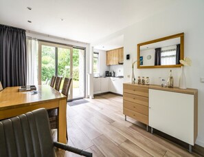 A modern kitchen with white cabinets, a wooden dining table, and a large window. - Home Near Vlissingen Beach (Vlissingen)