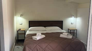 Un dormitorio con una cama grande, dos mesitas de noche y piso de baldosas.