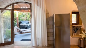 Eine Küche mit Kühlschrank, einer Steinwand und einem Fenster mit Vorhang.