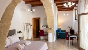 Ein Zimmer mit Bett, Schreibtisch, Sessel, Sofa und Esstisch.