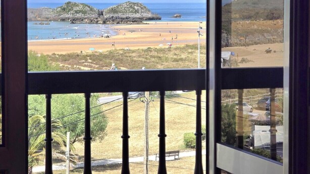 A balcony with a view of a beach and rocky outcrops.