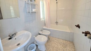 A bathroom with a sink, two toilets, a bathtub, and a shower.