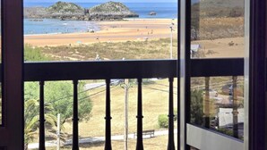 A balcony with a view of a beach and rocky outcrops.