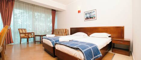 A hotel room with two beds, a chair, a table, and a nightstand.