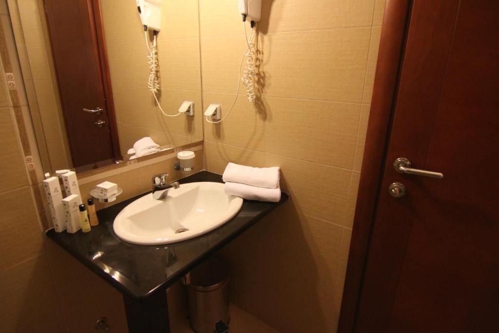 Un baño con lavamanos, espejo, toalla y artículos de aseo.