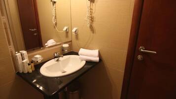 Un baño con lavamanos, espejo, toalla y artículos de aseo.