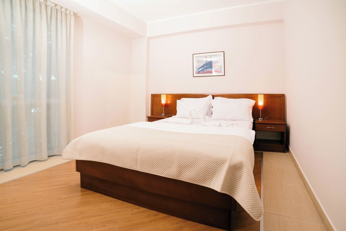 Una habitación de hotel con una cama, mesitas de noche, una lámpara y un cuadro en la pared.