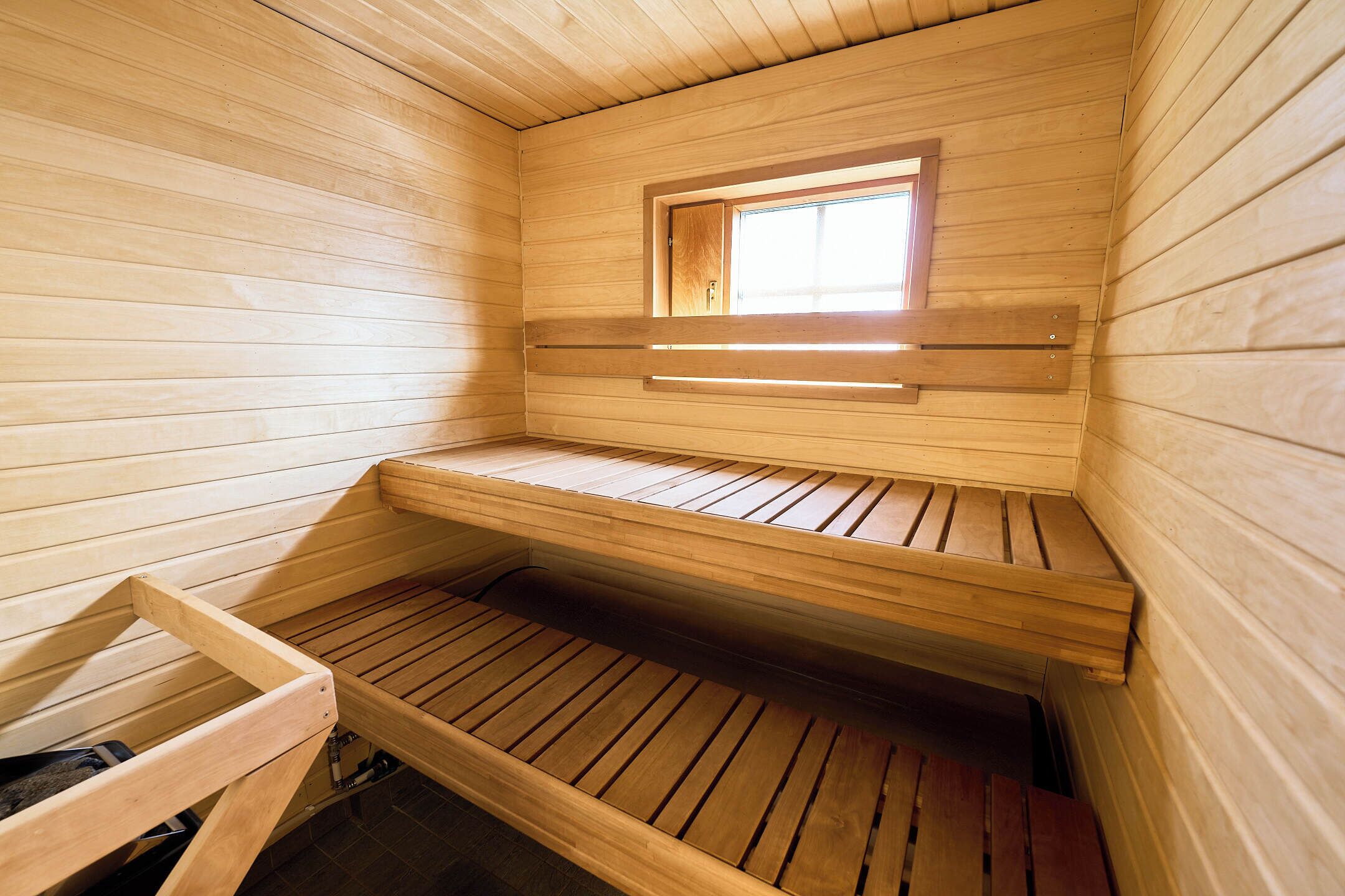 Un sauna avec des bancs en bois et une petite fenêtre.