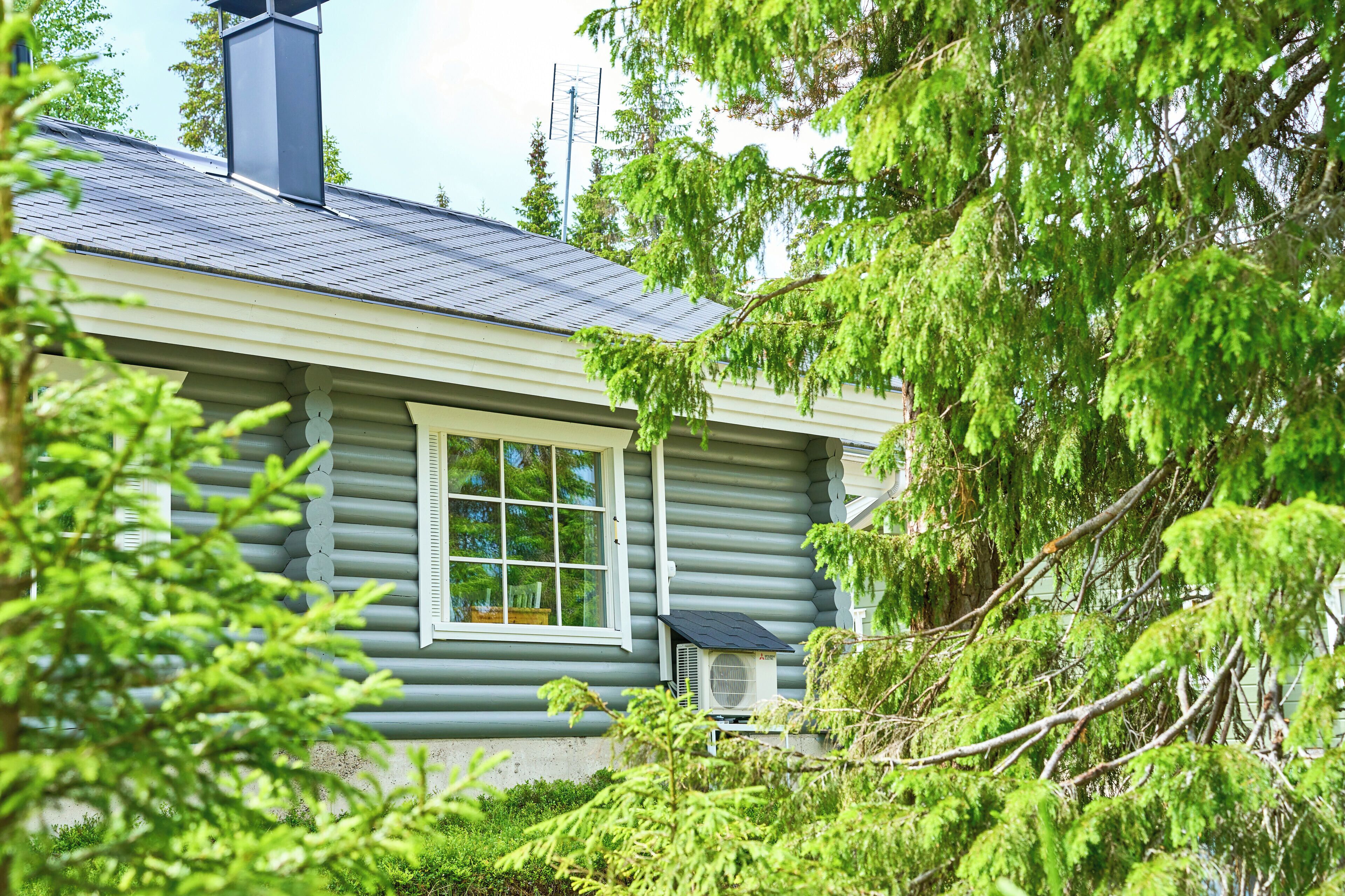 A log cabin with a chimney, a window, and an air conditioning unit.