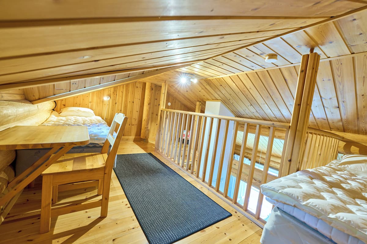 A wooden cabin with a loft bedroom, a dining area, and a small kitchen.