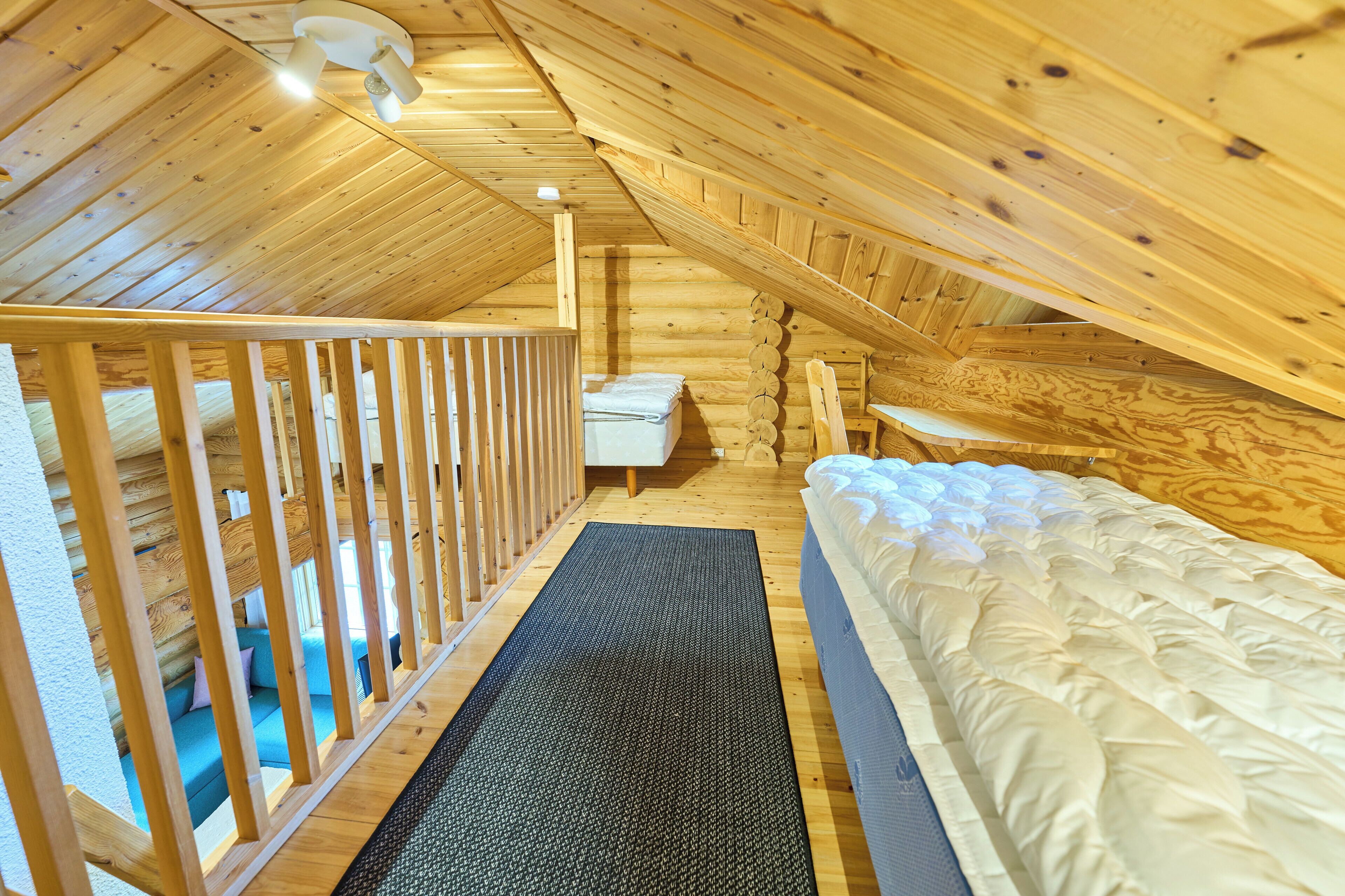 A wooden interior with a bunk bed, a small table, and a sofa.