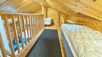 A wooden interior with a bunk bed, a small table, and a sofa.