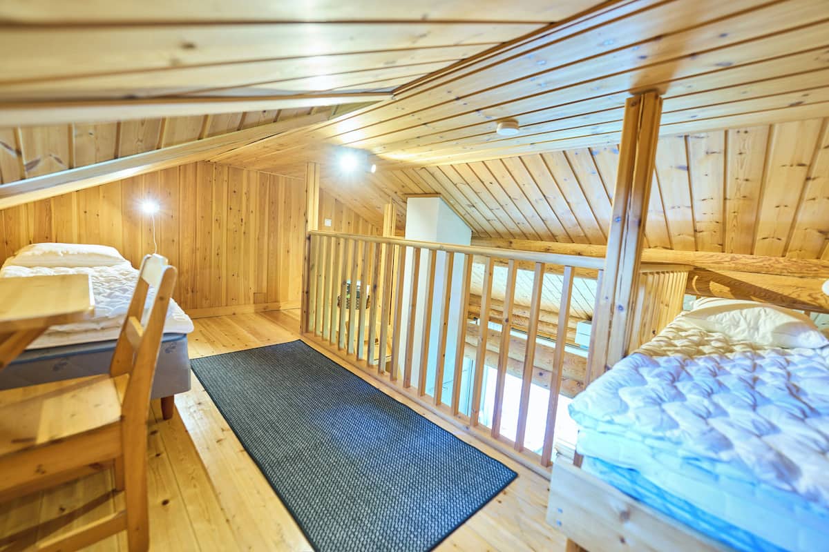 A wooden cabin with a loft bedroom, a balcony, and a dining area.