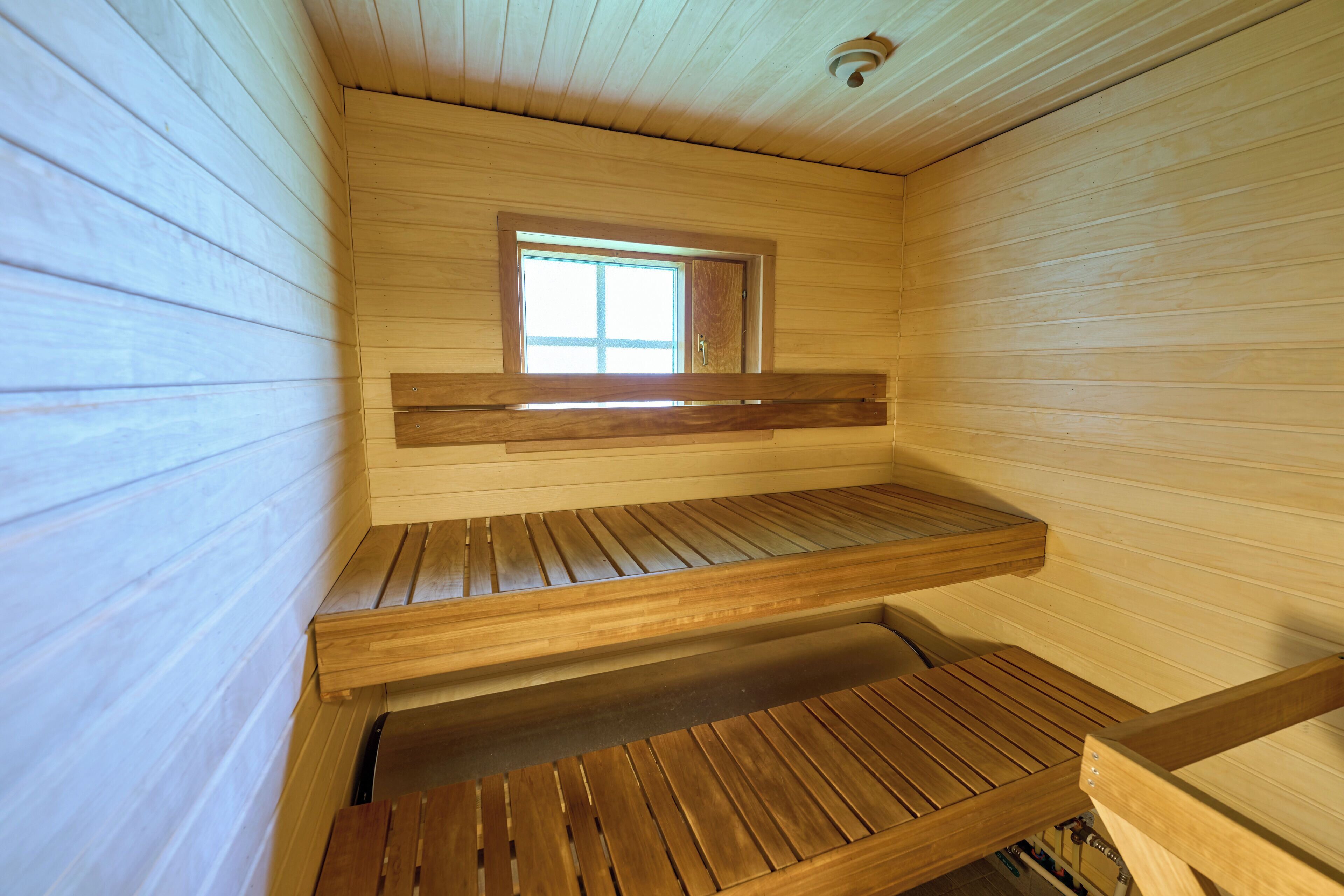Una sauna con bancos de madera y una ventana.