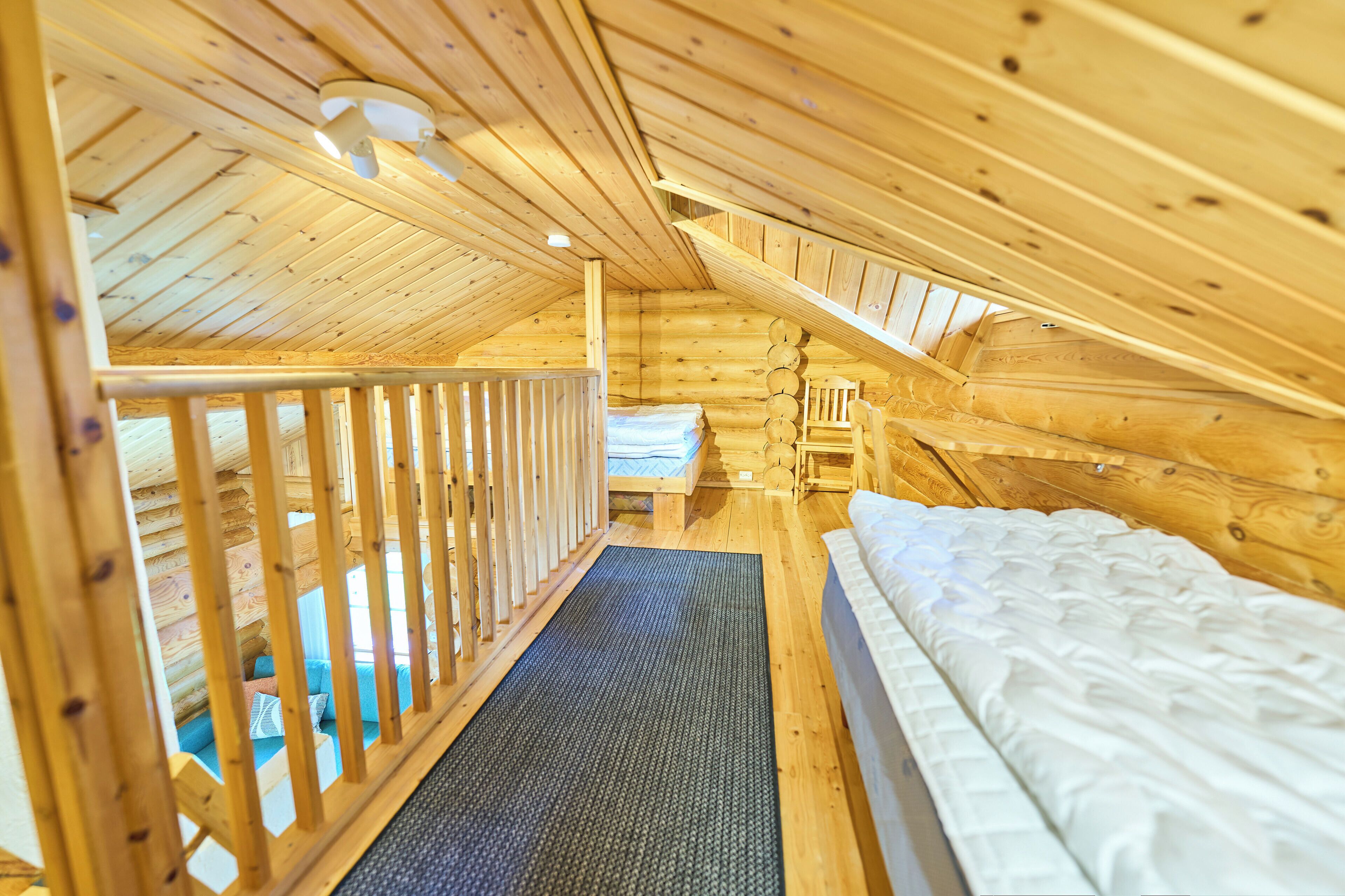 A wooden cabin with a loft bedroom, a small seating area, and a visible staircase.