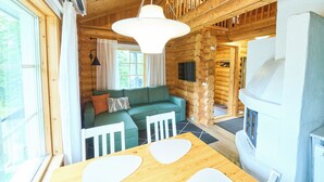 L'intérieur d'un chalet en bois, avec une table à manger, un canapé et une cheminée.
