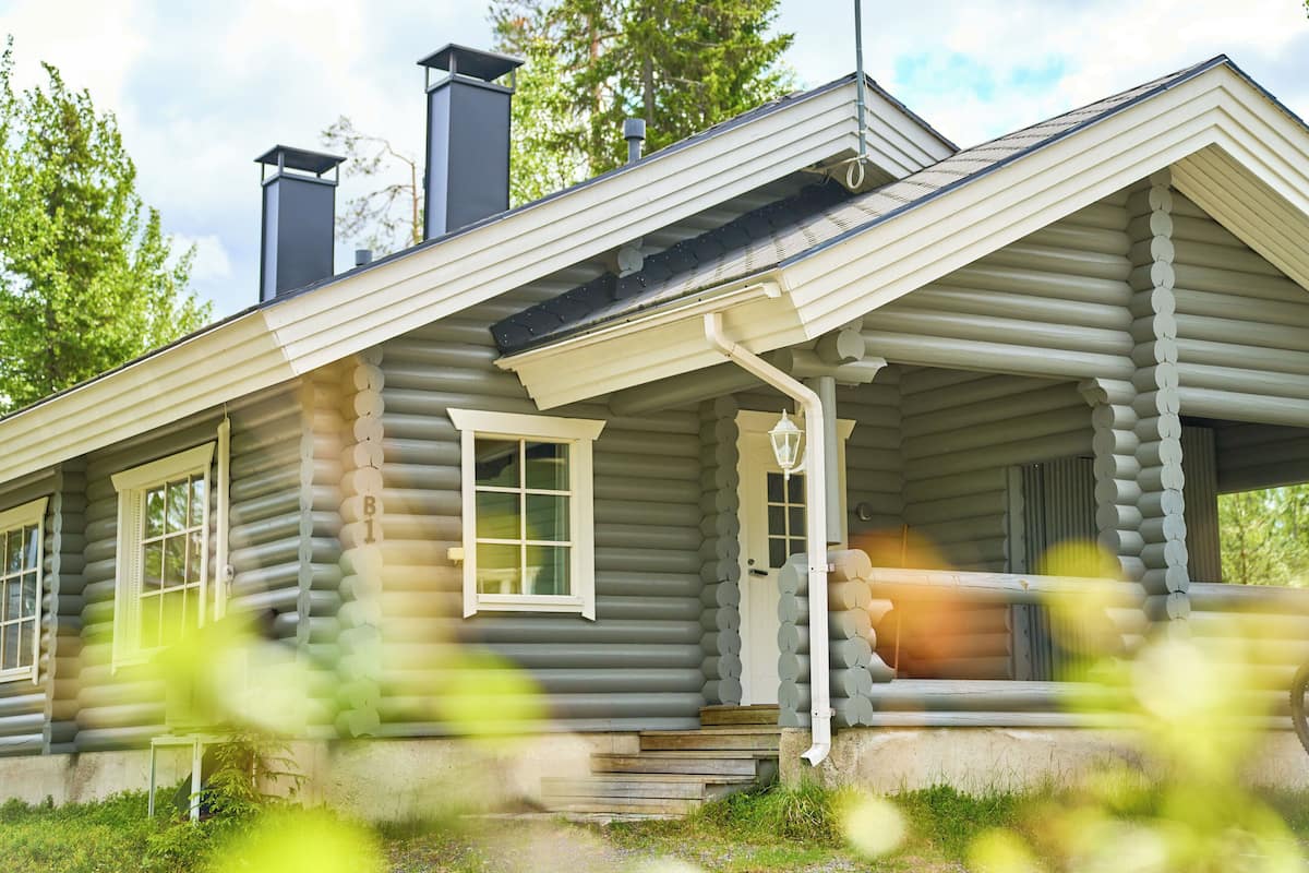 A log cabin with a porch, a chimney, and a window.
