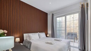 Ein modernes Hotelzimmer mit einem großen Bett, einem Schreibtisch mit Lampe und Blick auf die Terrasse.