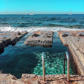 A rocky shoreline with clear water and metal ladders leading into the sea. - Stylish 1BR home in Sliema, with private terrace (Sliema)