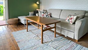 A living room with a sofa, a wooden coffee table, a small ottoman, and a patterned rug. - 4 Person Holiday Home in Farjestaden (Farjestaden)