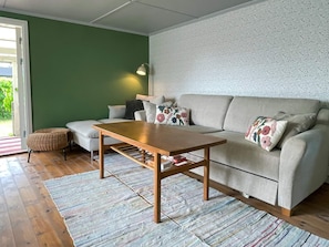 A living room with a sofa, a wooden coffee table, a small ottoman, and a patterned rug. - 4 Person Holiday Home in Farjestaden (Farjestaden)