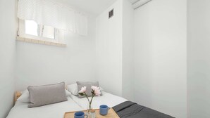 A bedroom with a bed, pillows, a tray with mugs, and a window with a curtain. - Cozy Apartment for 3 People | Great Location (Gliwice)